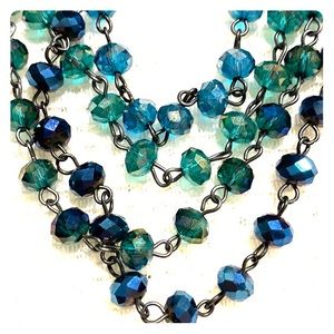 Collar necklace with green and teal beads.